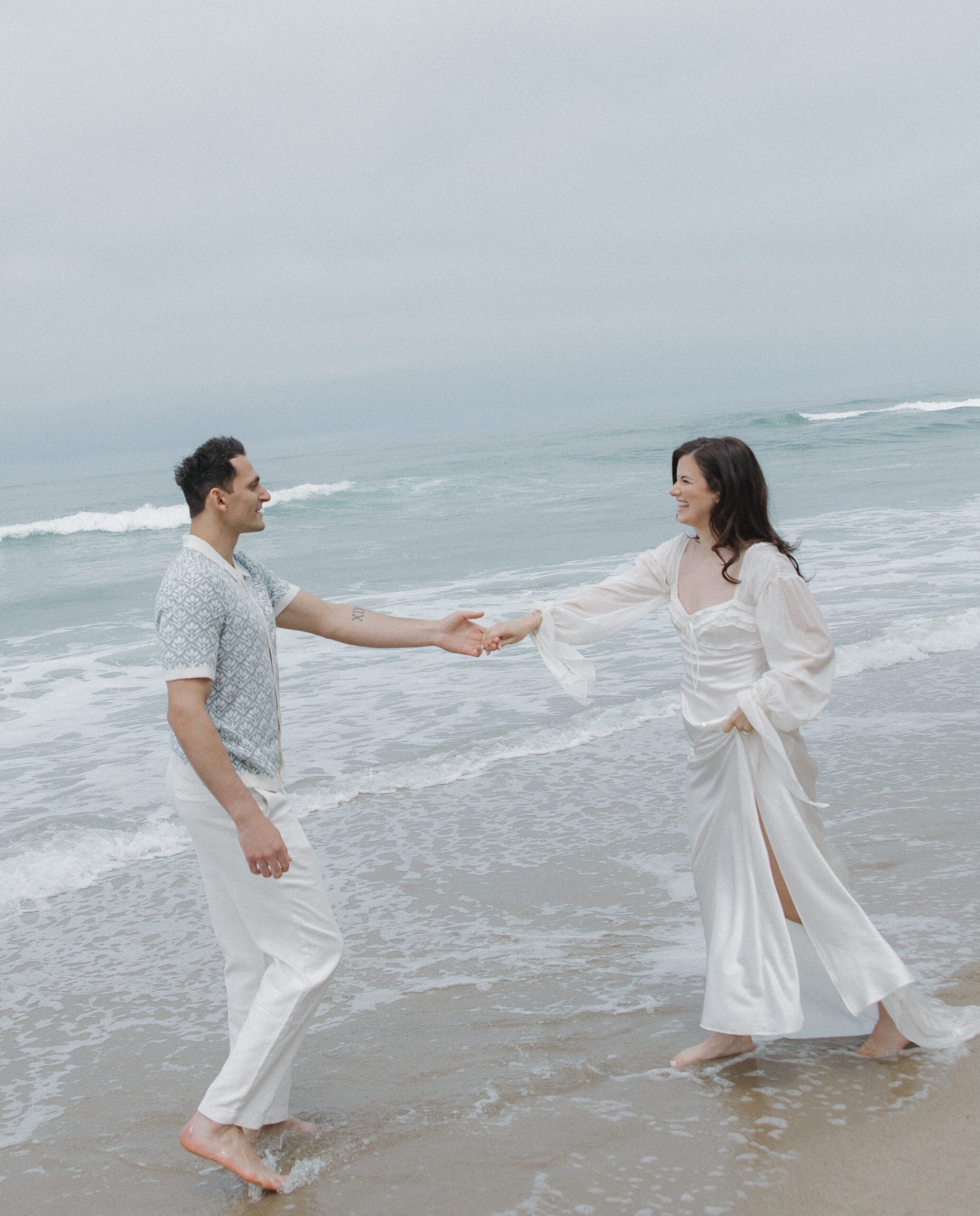 A couple laughing during their beach engagement photos