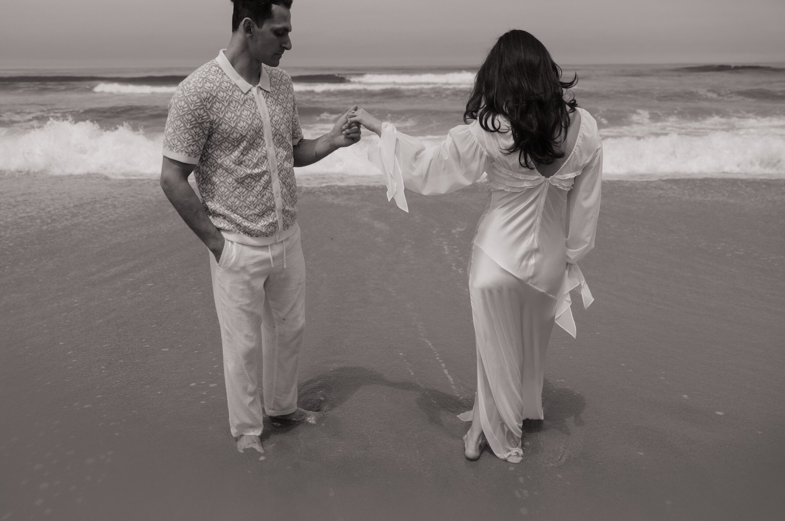 A couple holding hands during their beach engagement photos