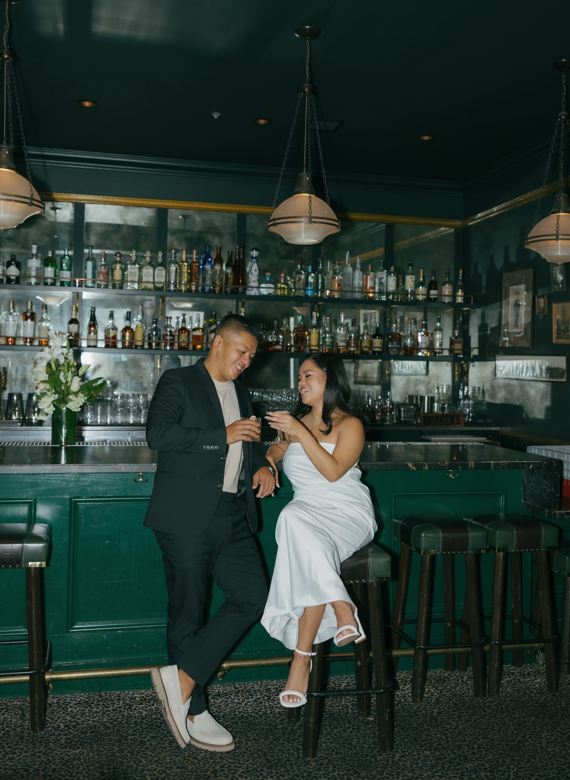 A couple posing in classy engagement photo shoot outfit ideas for a bar engagement photoshoot