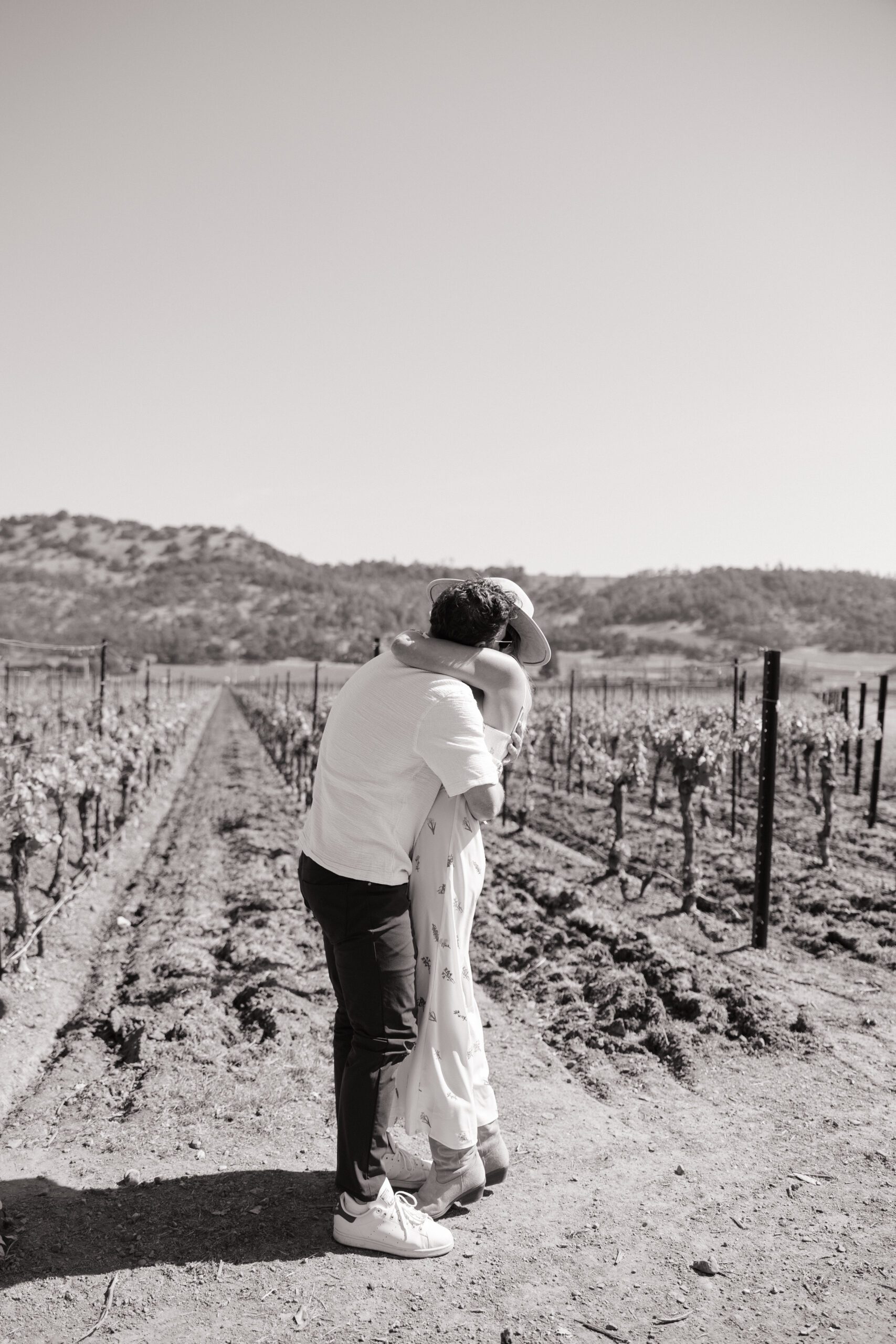 A black and white photo of a couple hugging at their vineyard proposal, a romantic proposal idea