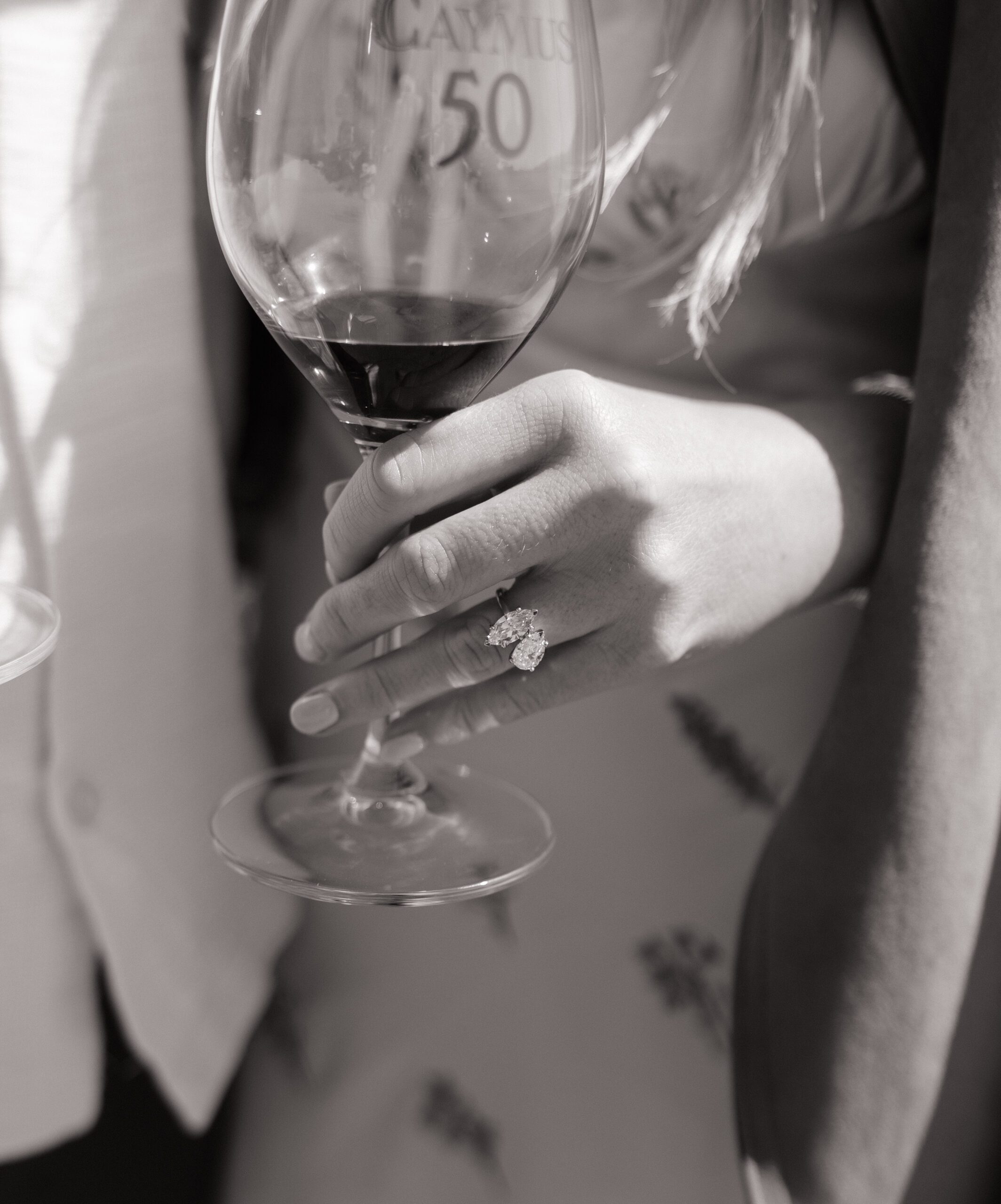 A woman holding a wine glass and showing off her engagement ring