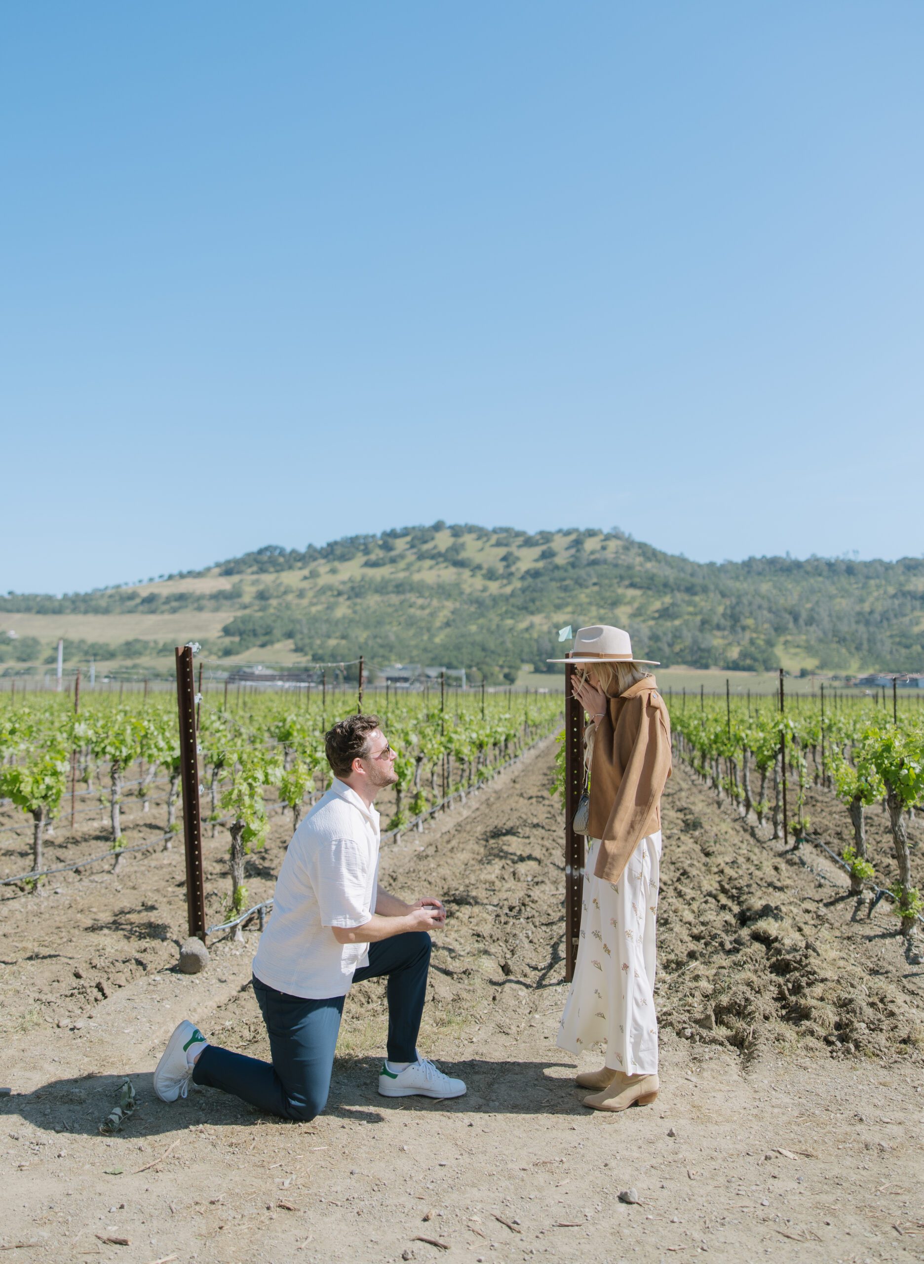A woman reacting to a surprise proposal in a vineyard, showing off romantic proposal ideas