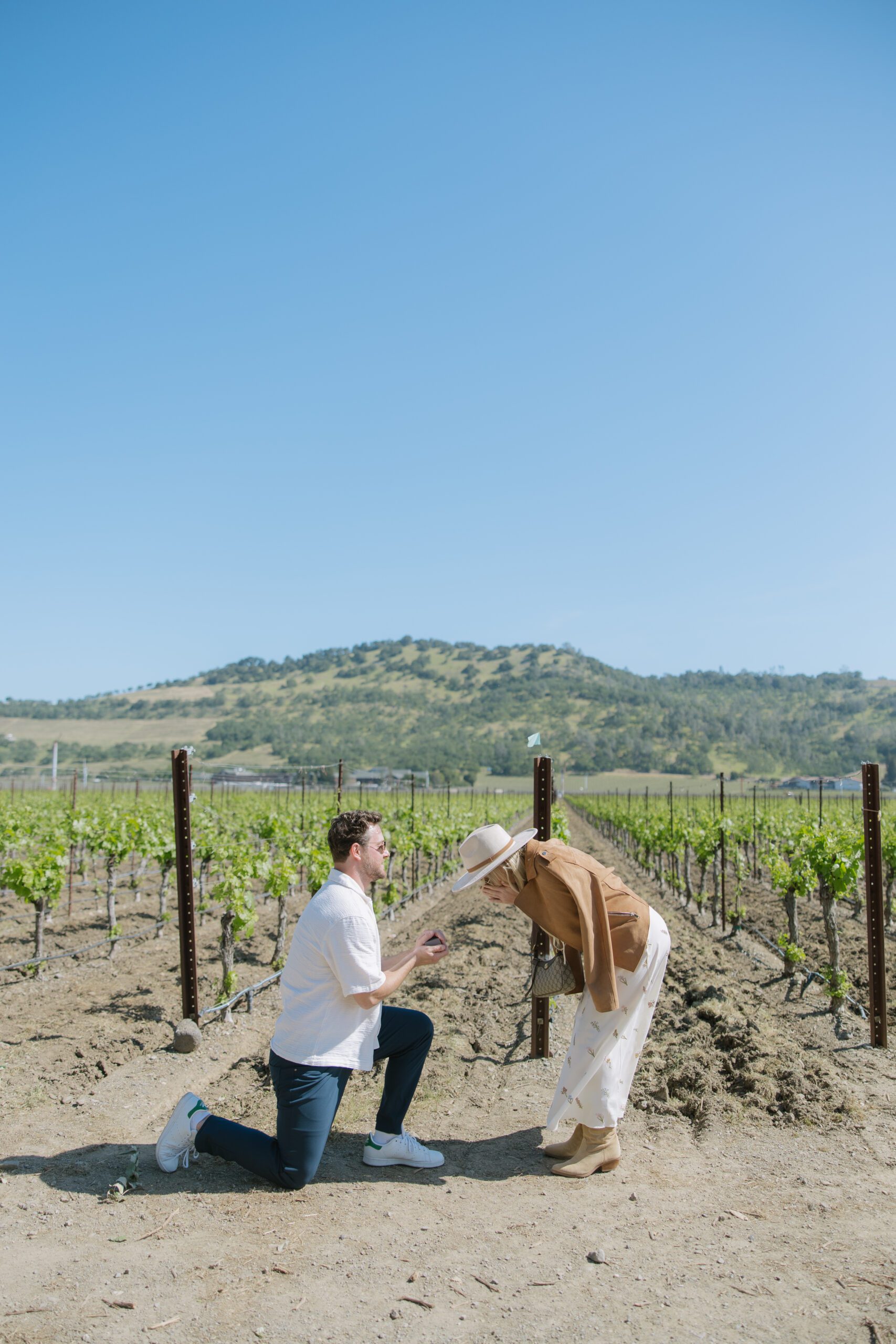 A woman reacting to a surprise proposal in a vineyard, showing off romantic proposal ideas