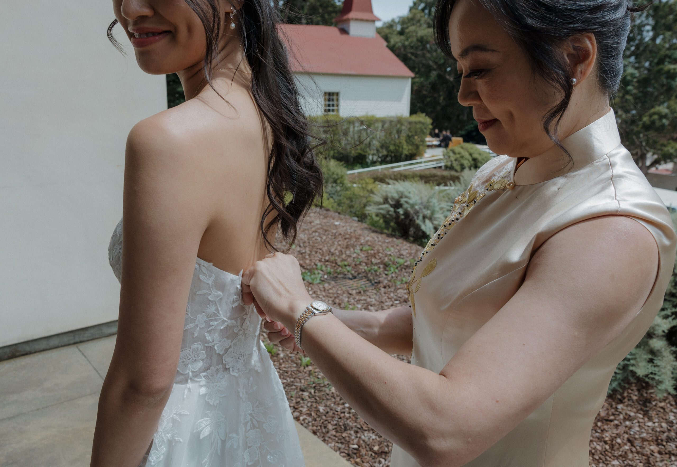 A mother helping her daughter into her wedding dress
