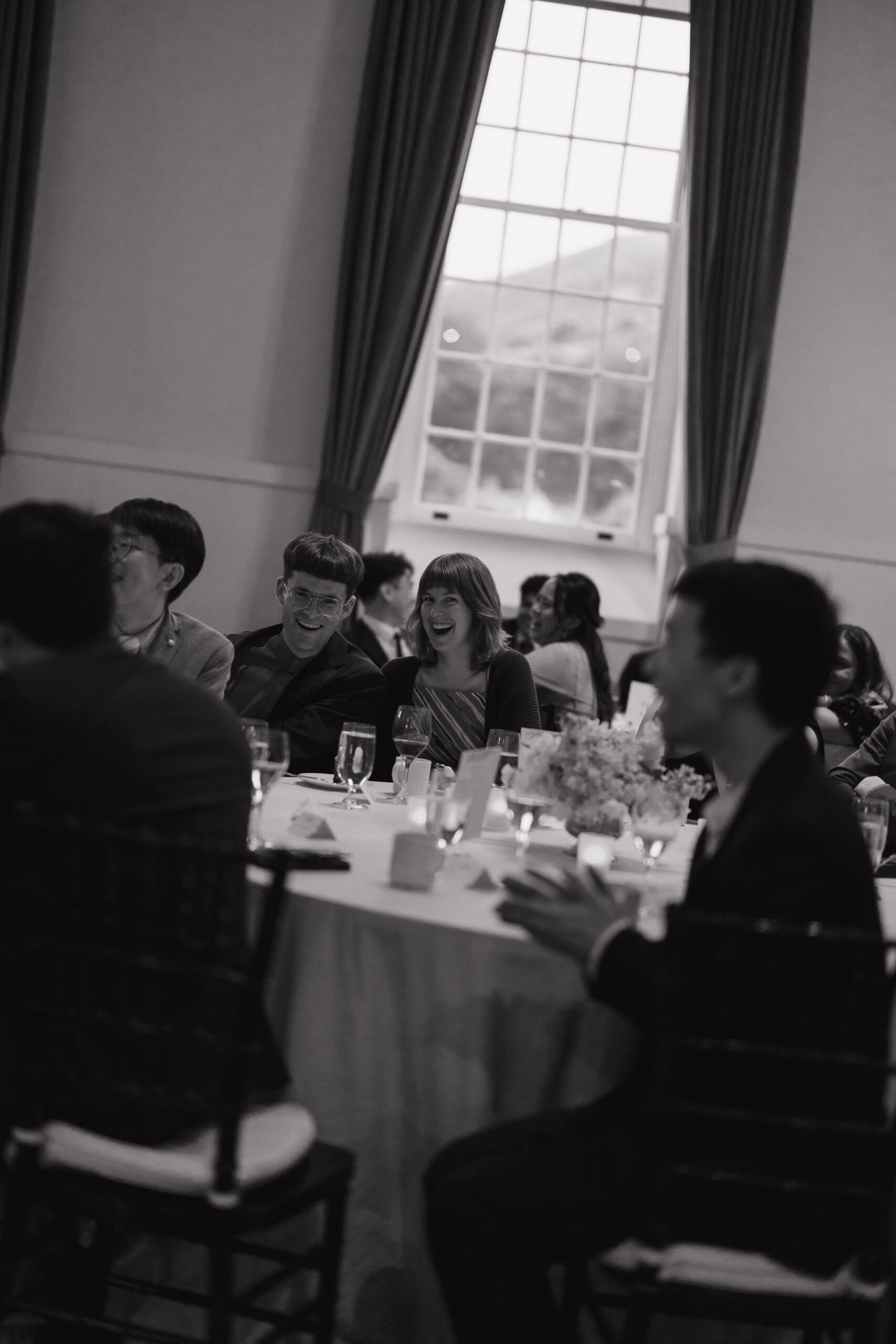 A black and white candid photo of wedding guests at a reception