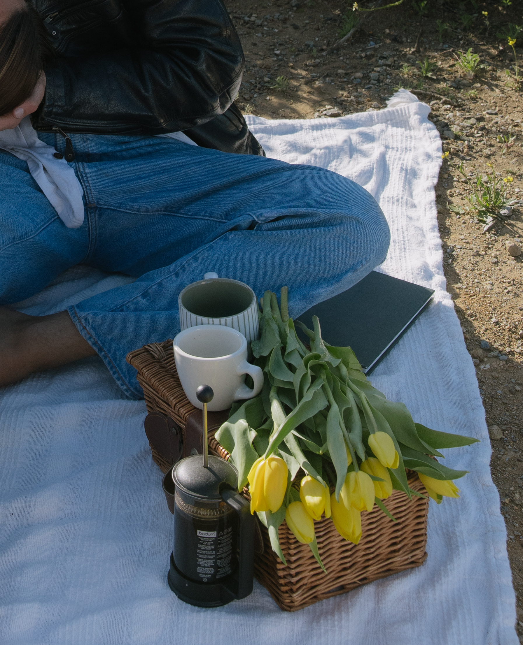 A picnic setup with tulips and coffee for a beach engagement photoshoot