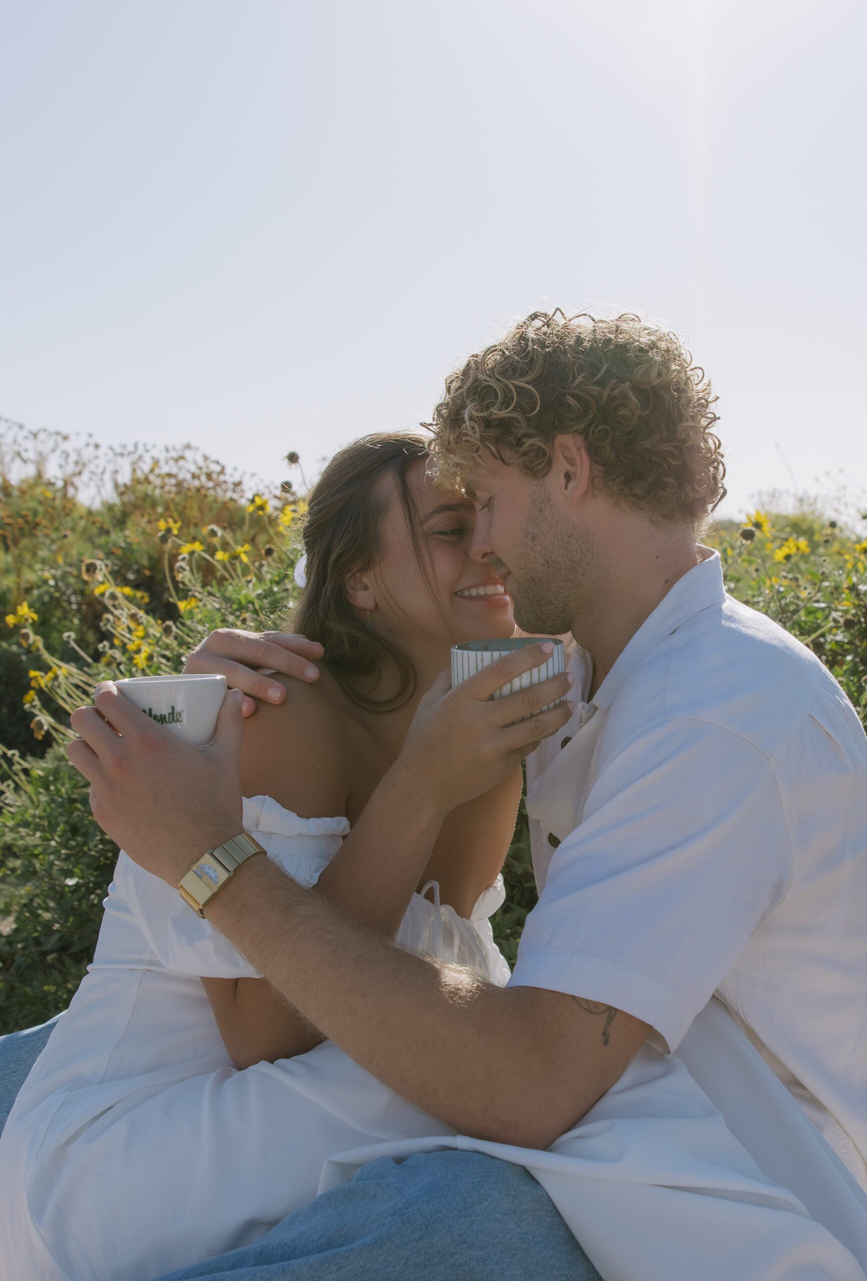A couple leaning in for a kiss during their picnic beach engagement pictures