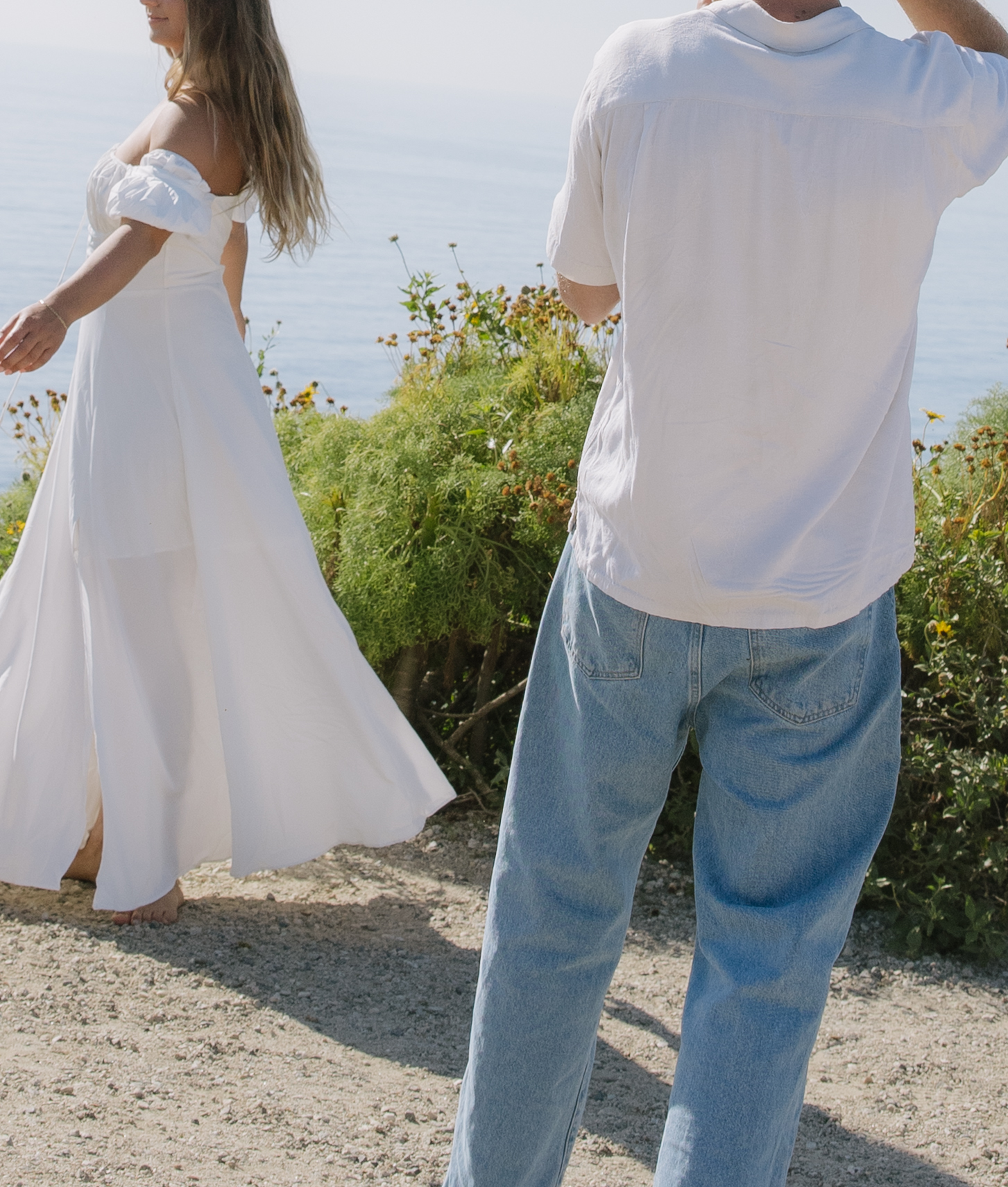 A man standing behind his spinning fiancee during beach engagement pictures