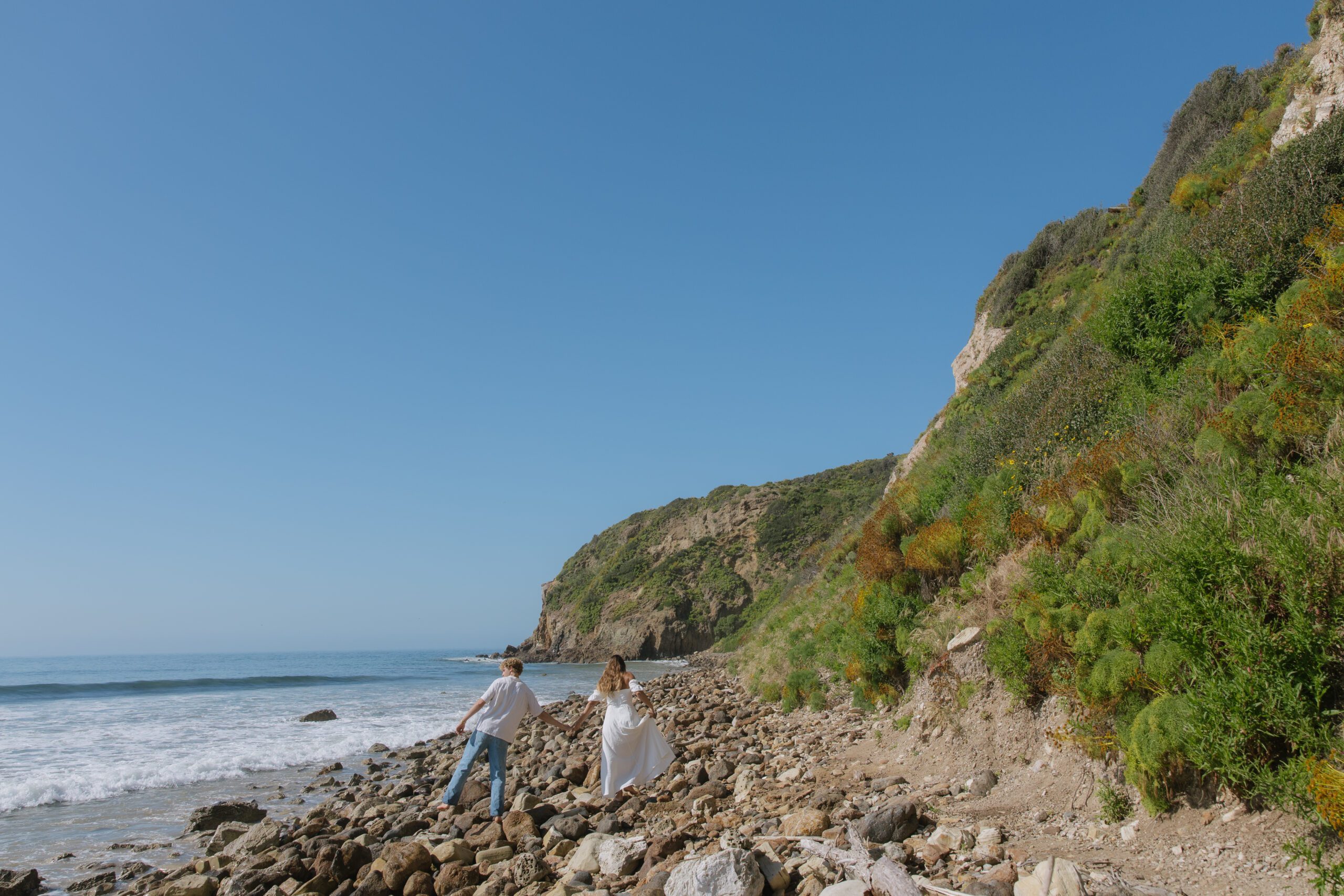 A couple taking Malibu Beach photos in front of a rock formation