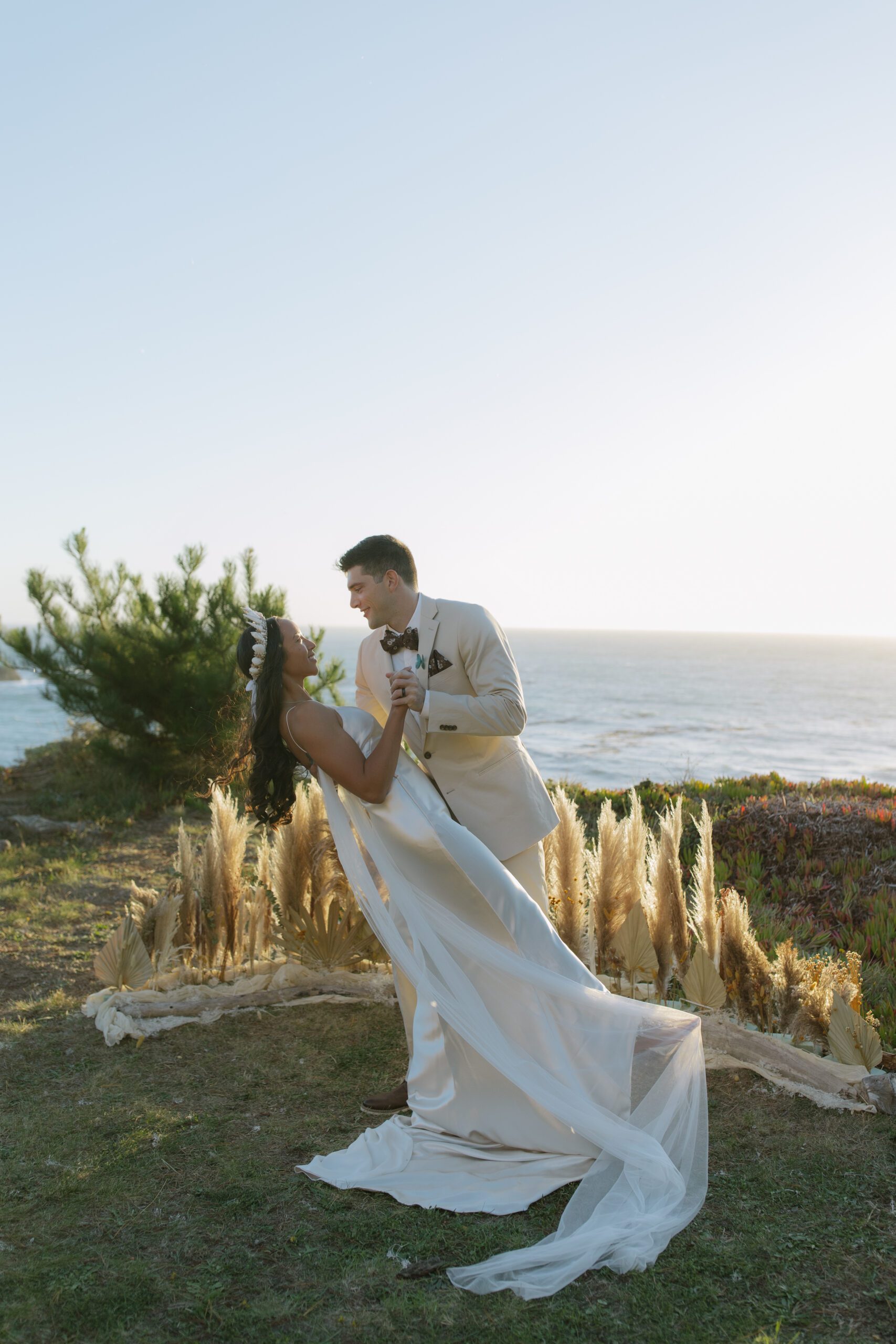 A bride and groom taking photos at their waterfront wedding ceremony