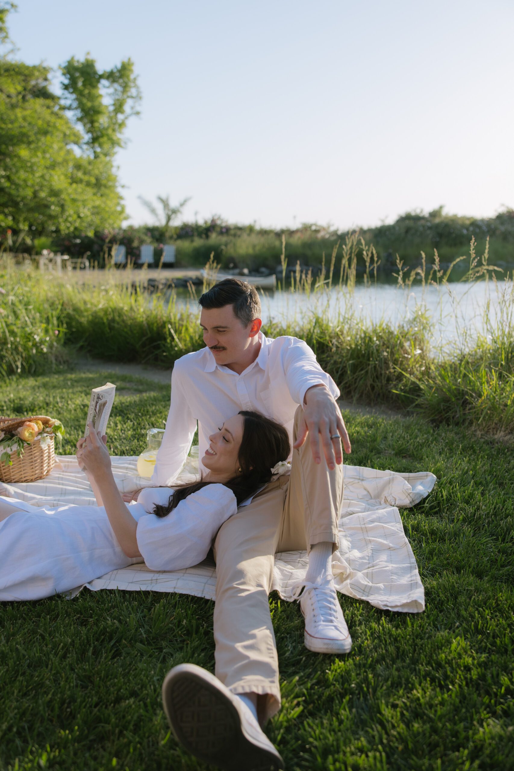 A woman reading at a picnic for her engagement photoshoot