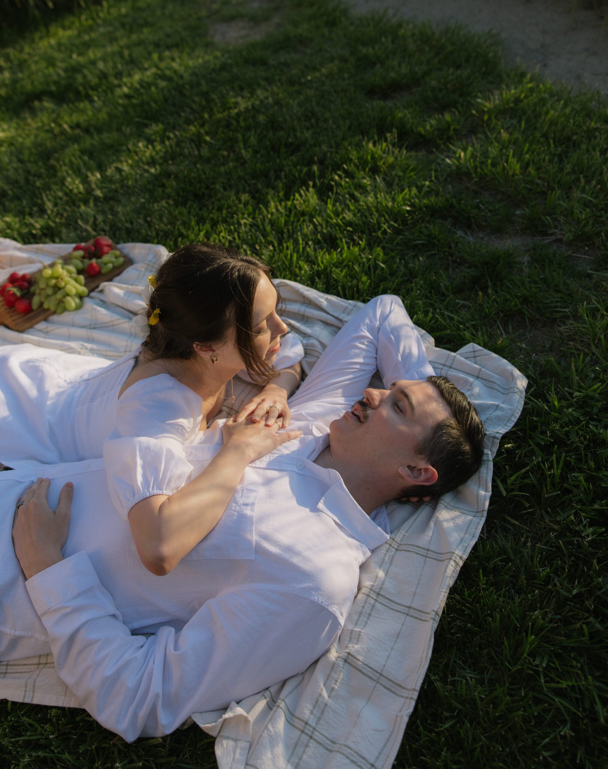 A woman lying on her fiances chest at their engagement photo location, cavaignac