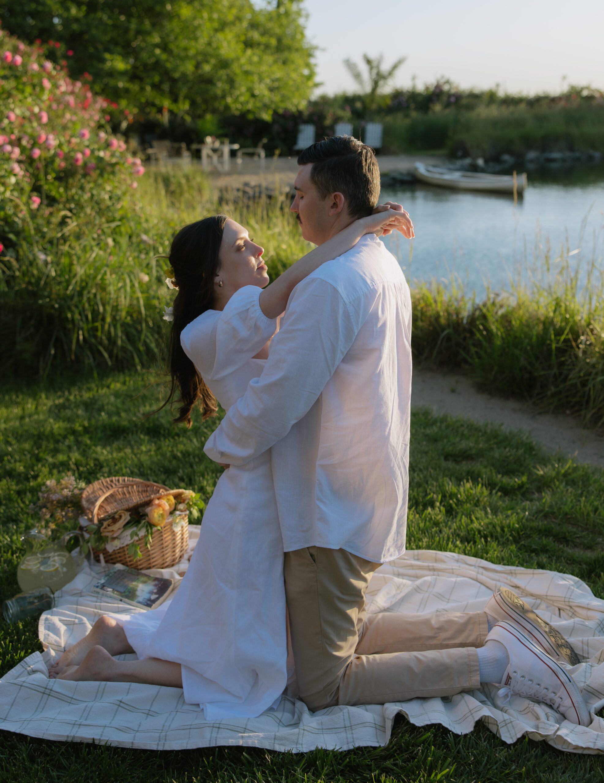 A couple posing for engagement photos in a picnic setup