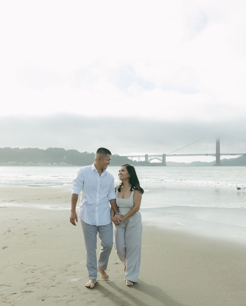 A couple walking along Crissy Field Beach for engagement photos
