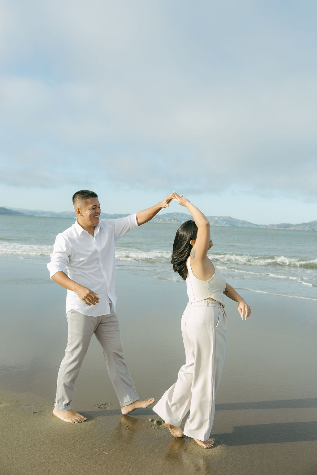 A couple dancing for engagement photos on the beach
