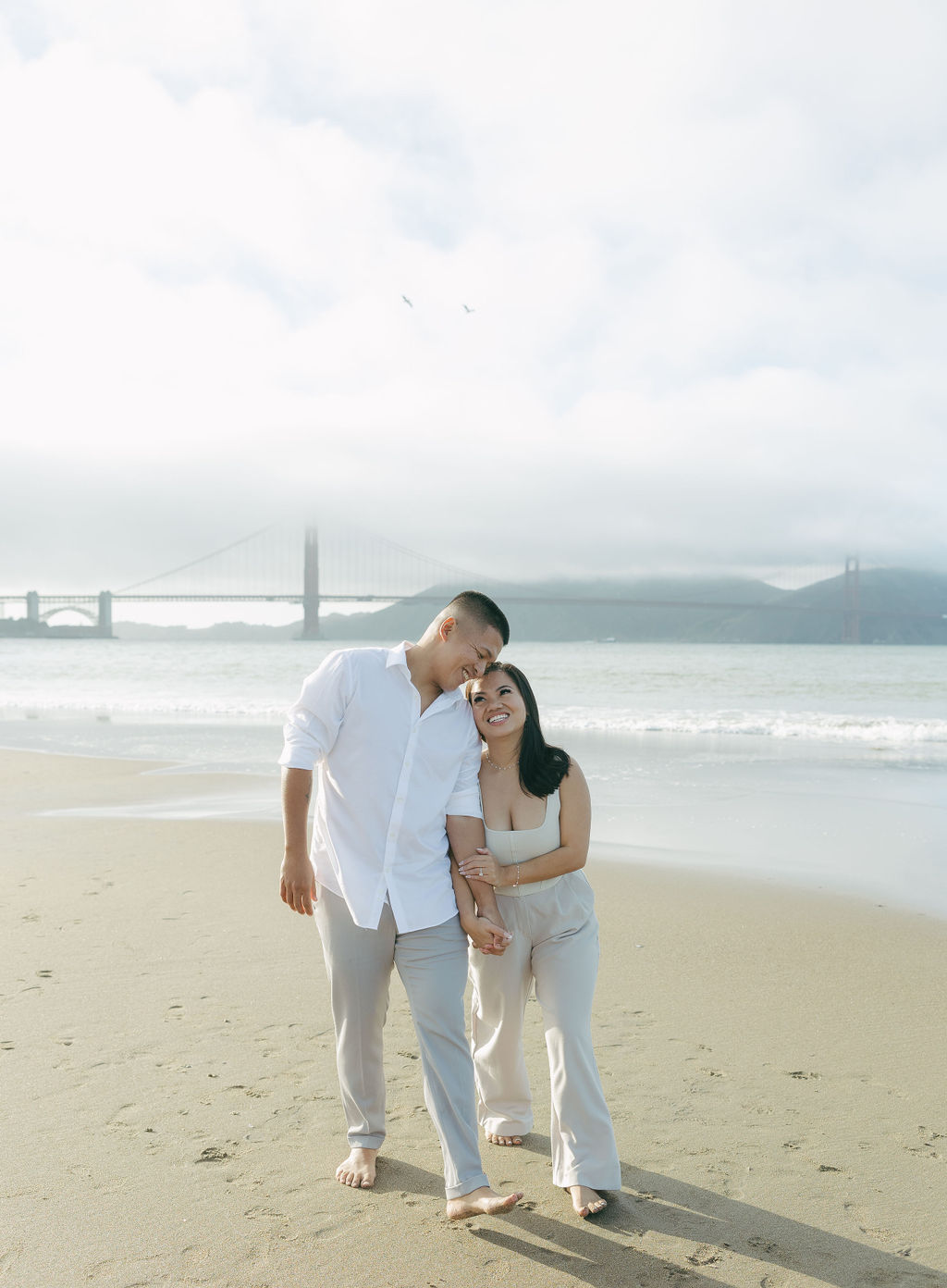 A couple walking along Crissy Field Beach for engagement photos