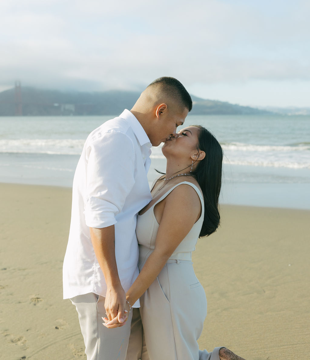 A couple kissing for beach engagement photos on Crissy Field beach