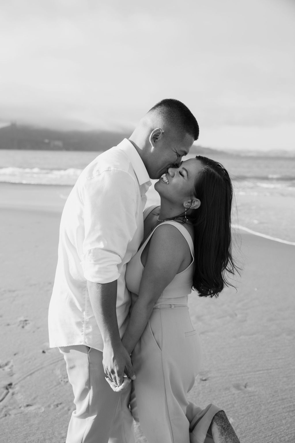 A couple laughing together during their beach engagement photoshoot