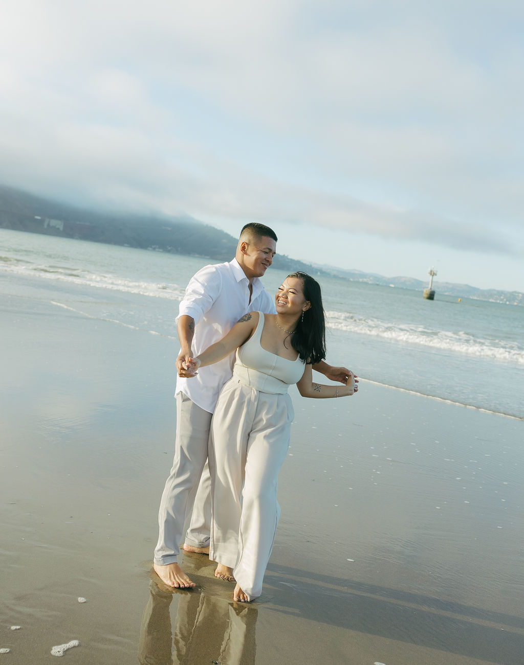 A candid engagement photo of a couple on a beach
