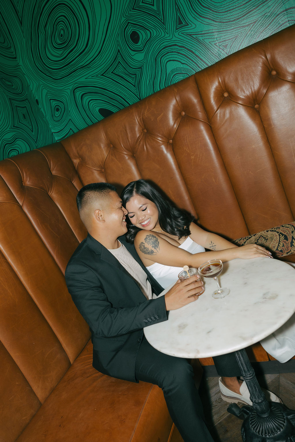 A couple in a booth taking bar engagement photos