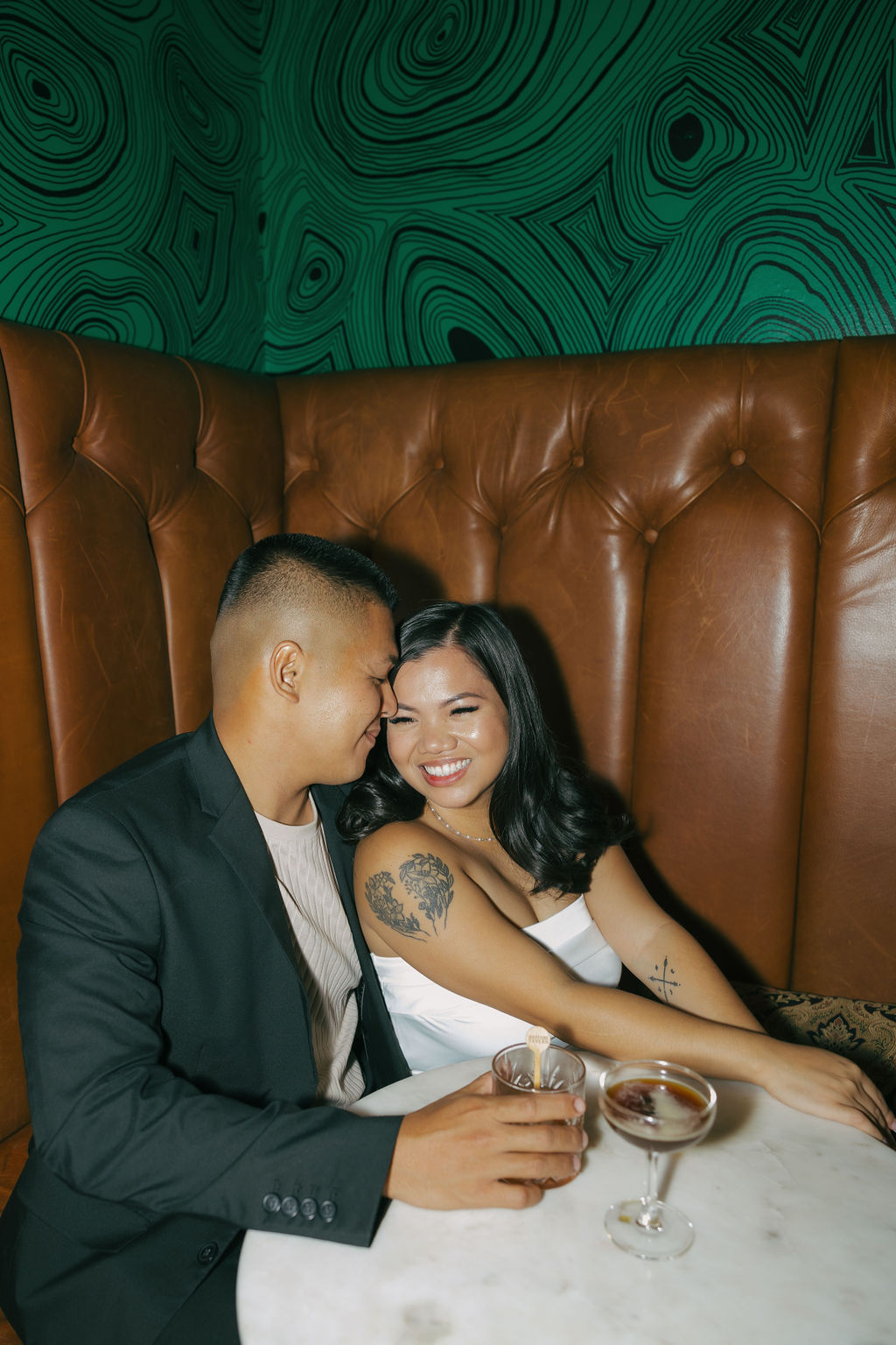 A couple in a booth taking bar engagement photos