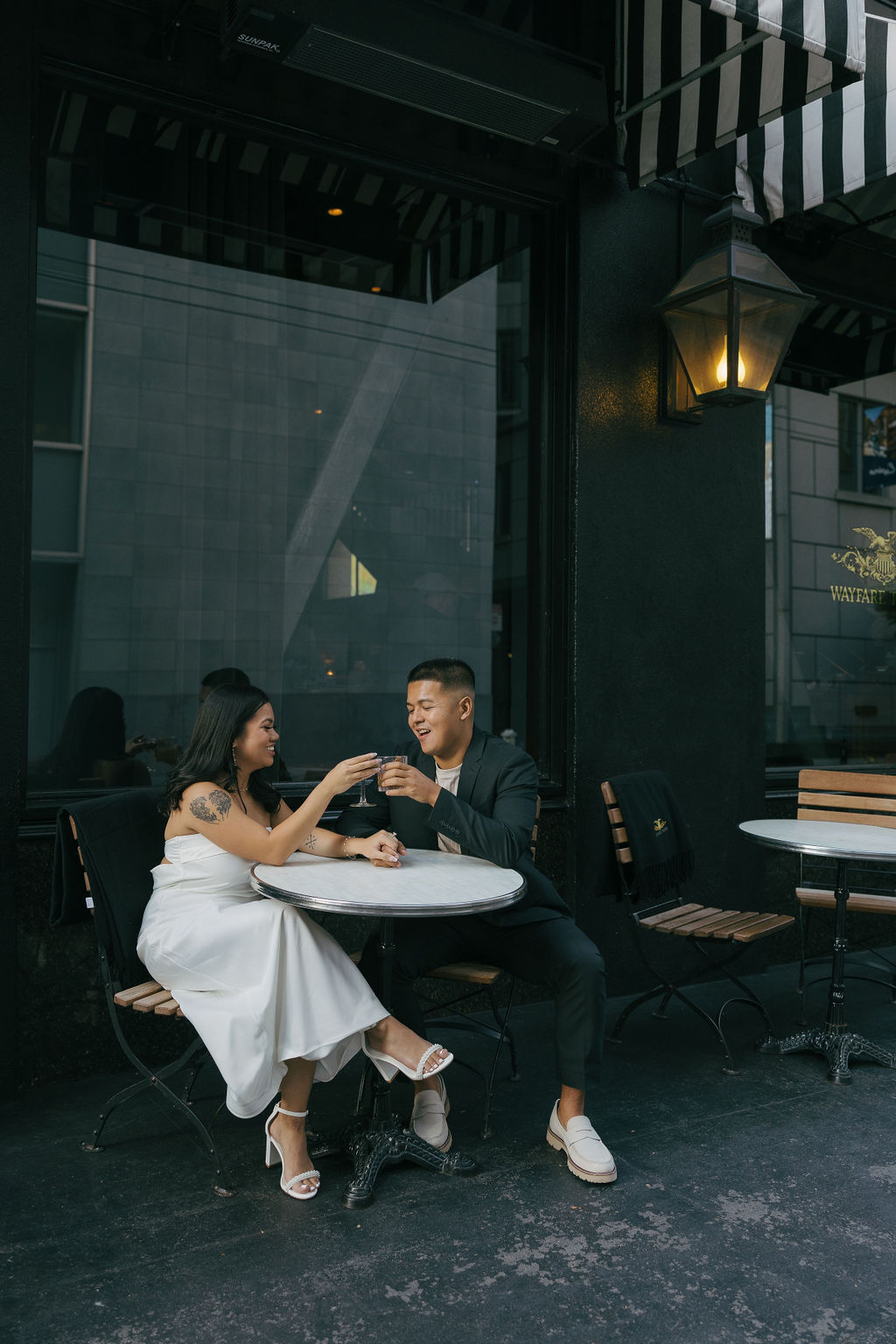 A couple sitting outside of a bar for engagement photos