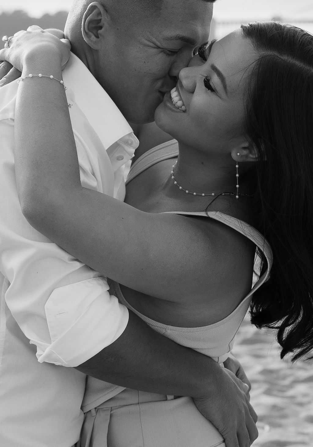 A couple laughing together during their beach engagement photoshoot