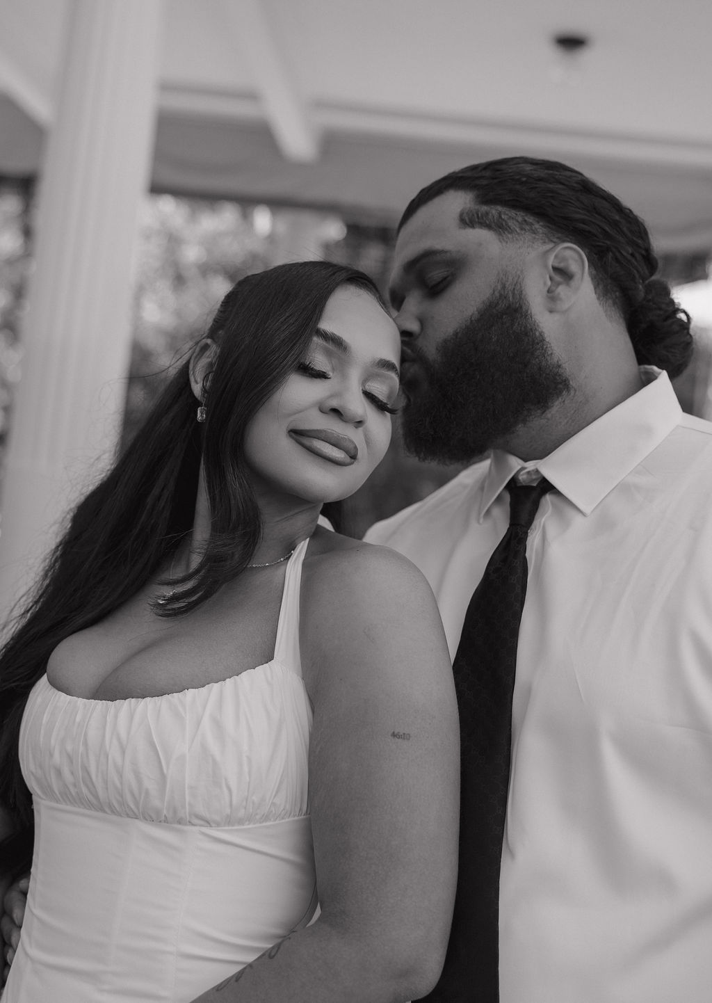 A black and white photo of a groom kissing his wife