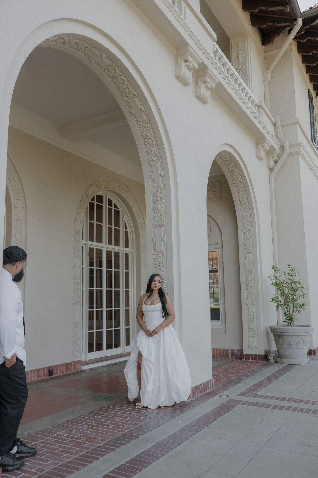 A bride and groom posing for wedding photos underneath arches
