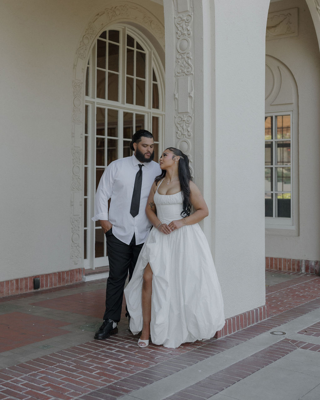 A bride and groom posing for wedding photos underneath arches