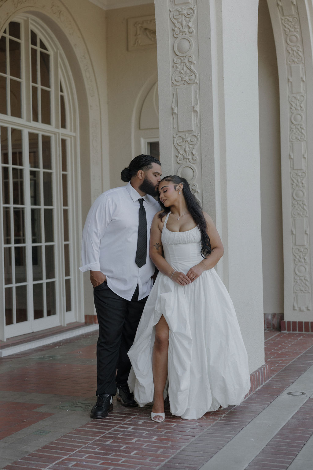A bride and groom posing for wedding photos underneath arches