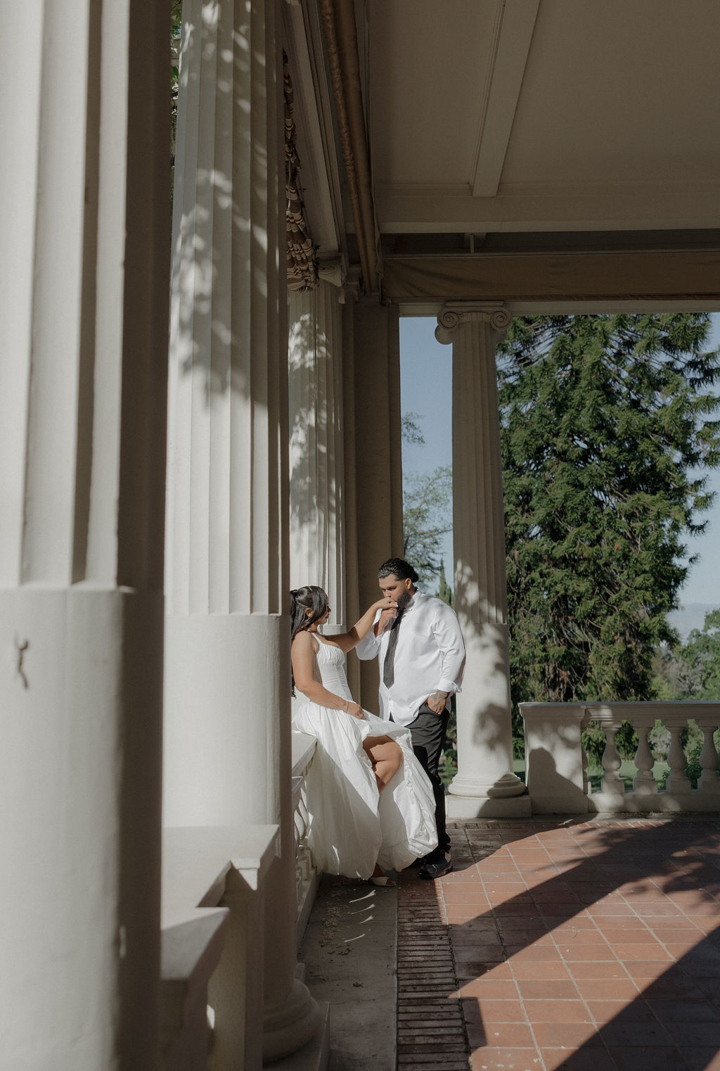 A bride and groom on a porch taking wedding photos