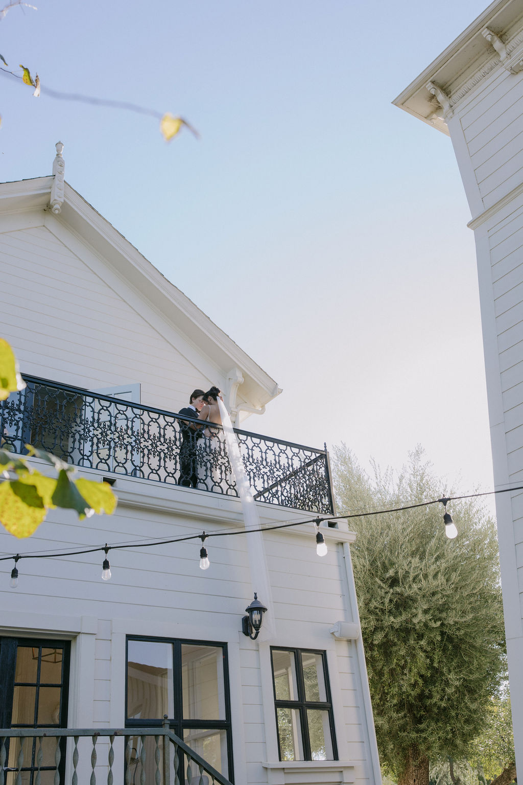 a bride and groom posing for wedding photos on a wedding venue balcony