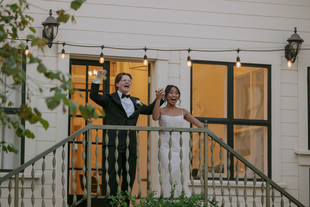 A bride and groom cheering from a Balcony