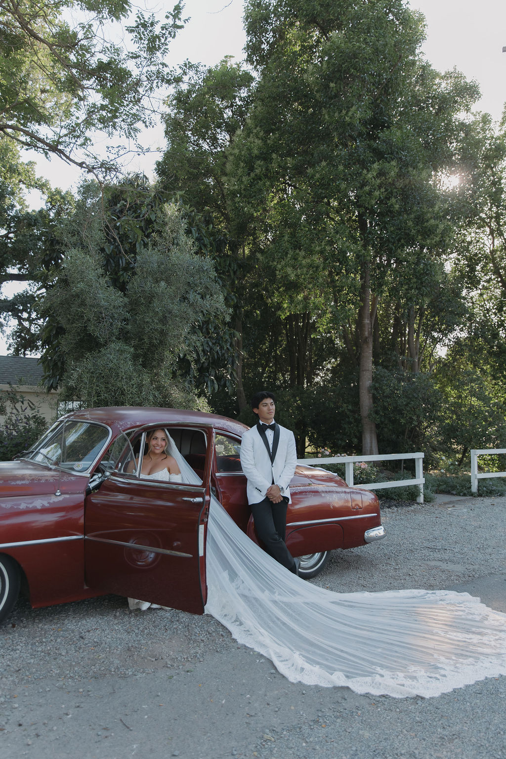 A bride and groom taking wedding photos with a vintage car