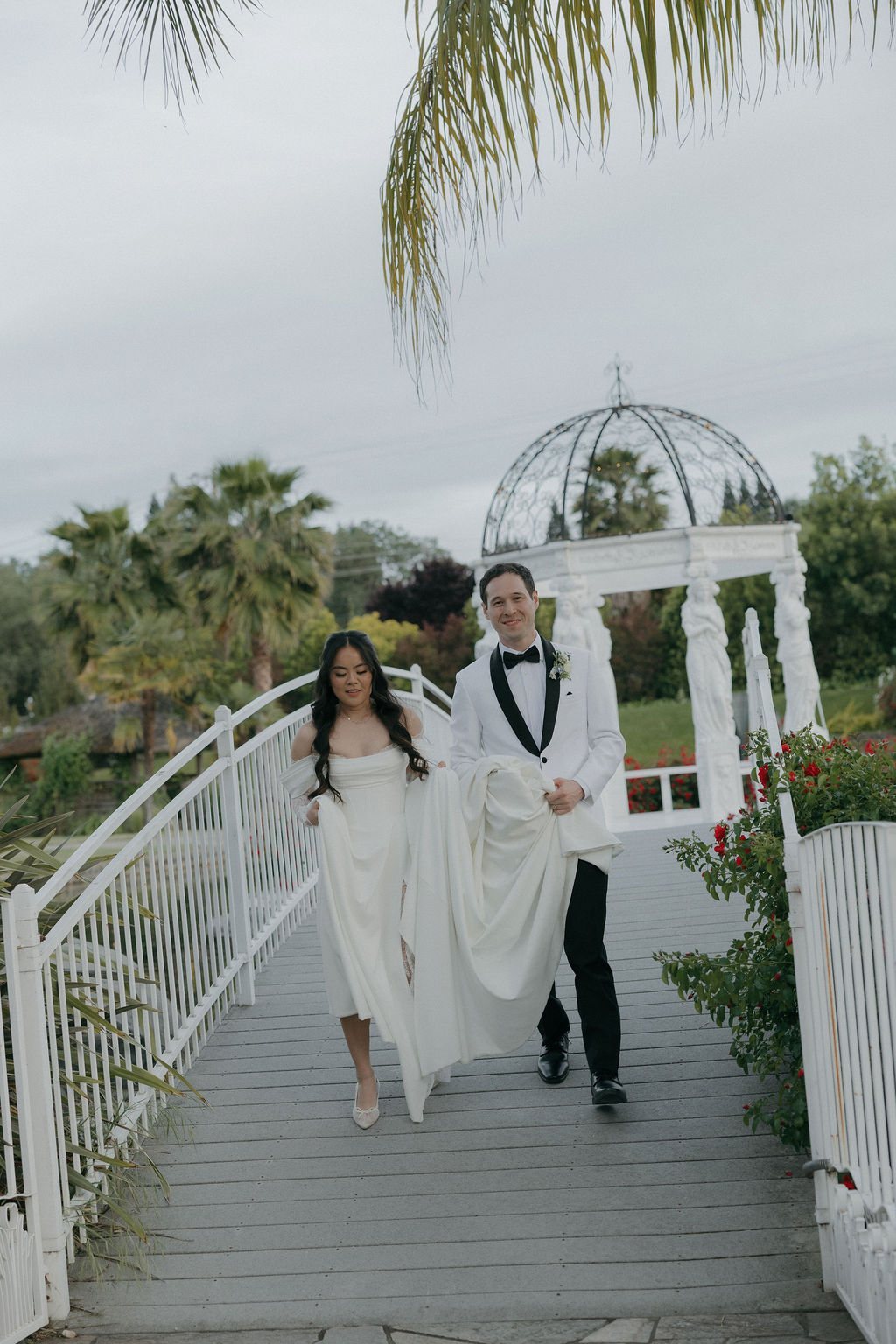 A bride and groom taking photos on a bridge
