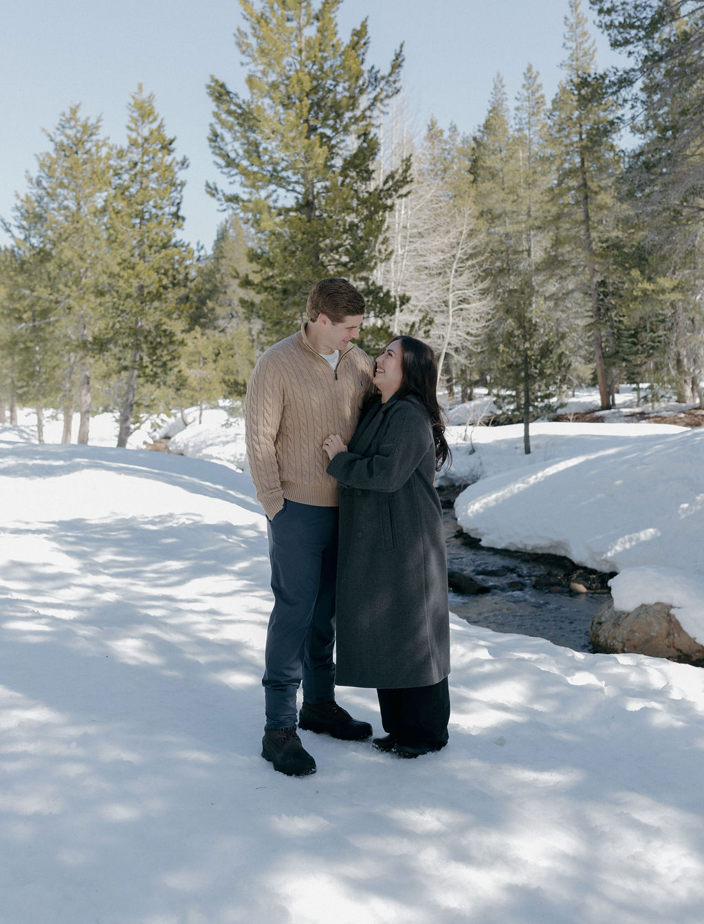 A couple standing in the snow for their engagement photos
