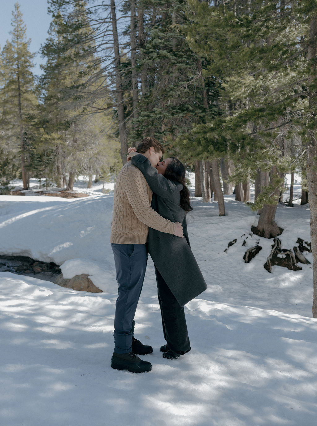 A couple posing for winter engagement photos in the snow