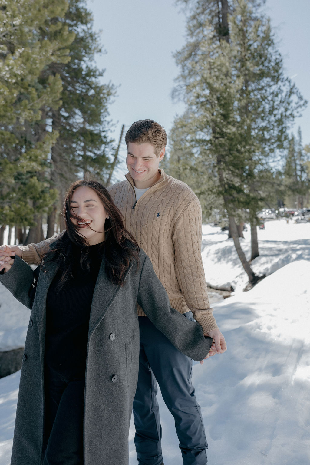 A couple taking snowy engagement photos