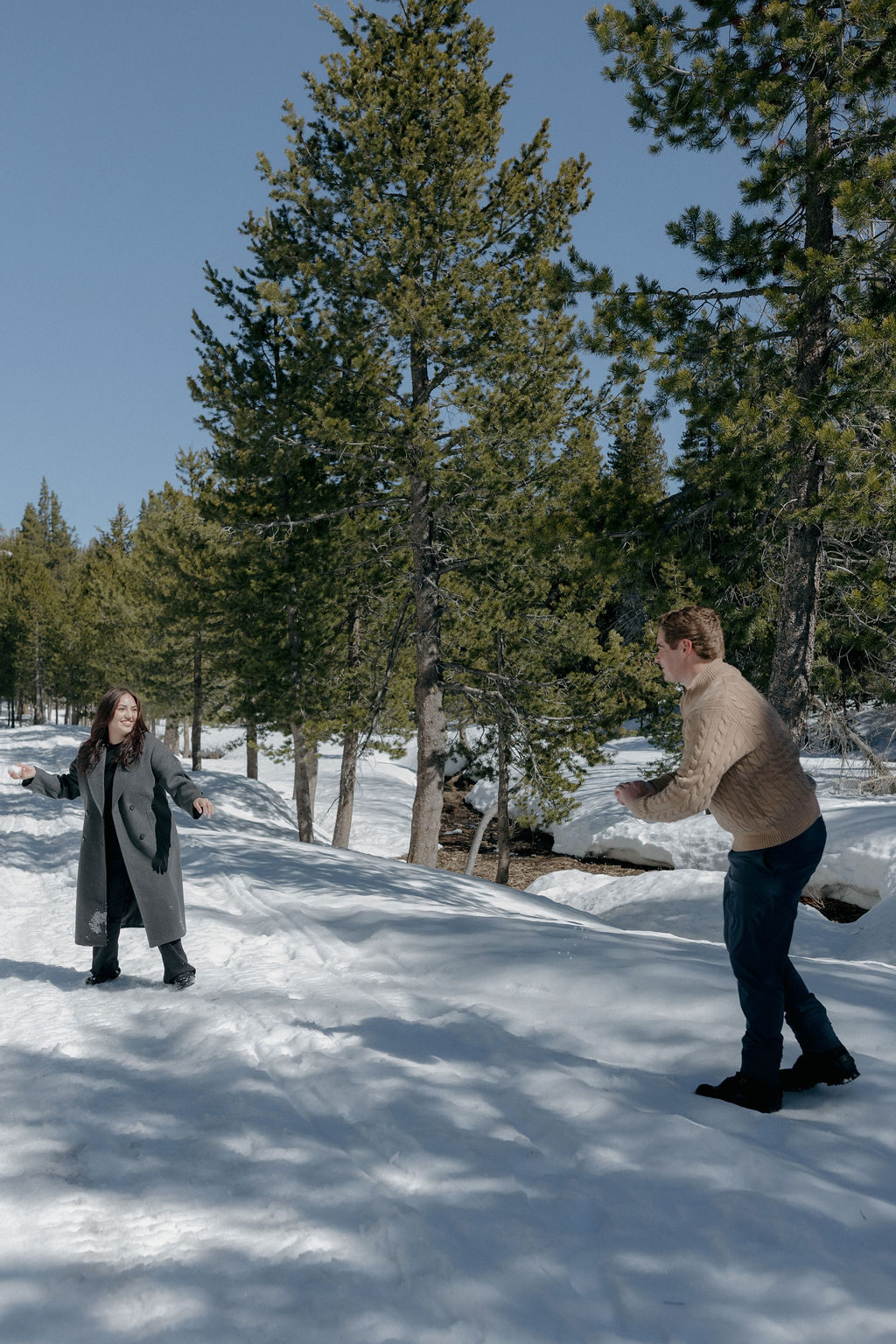 A couple playing in the snow for their engagement photos