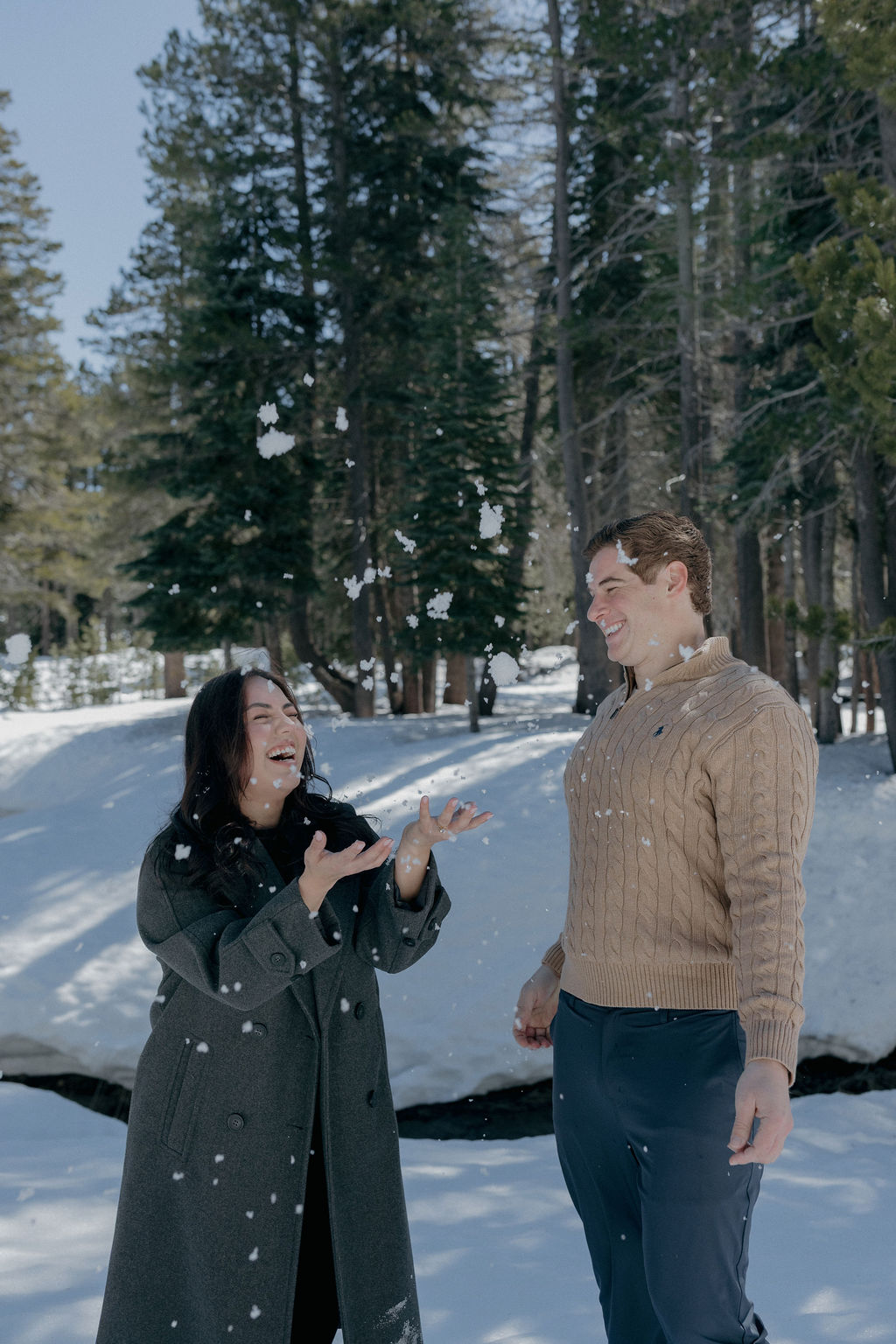 A couple playing in the snow for their engagement photos