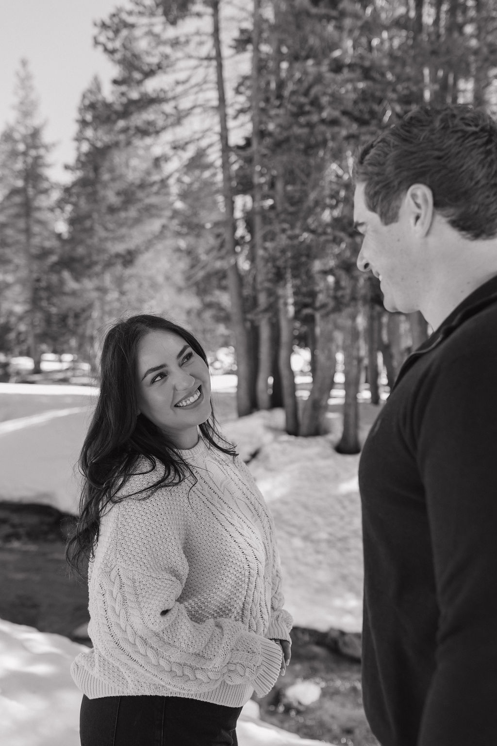 A woman smiling at her fiance during winter engagement photos