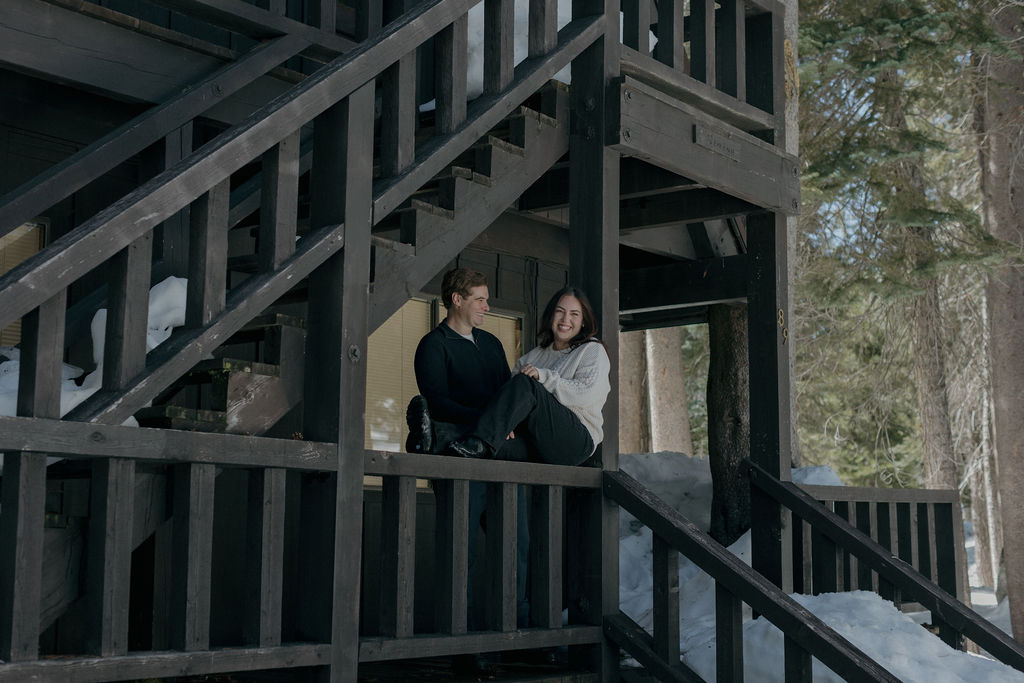 A couple at a cabin taking winter engagement photos