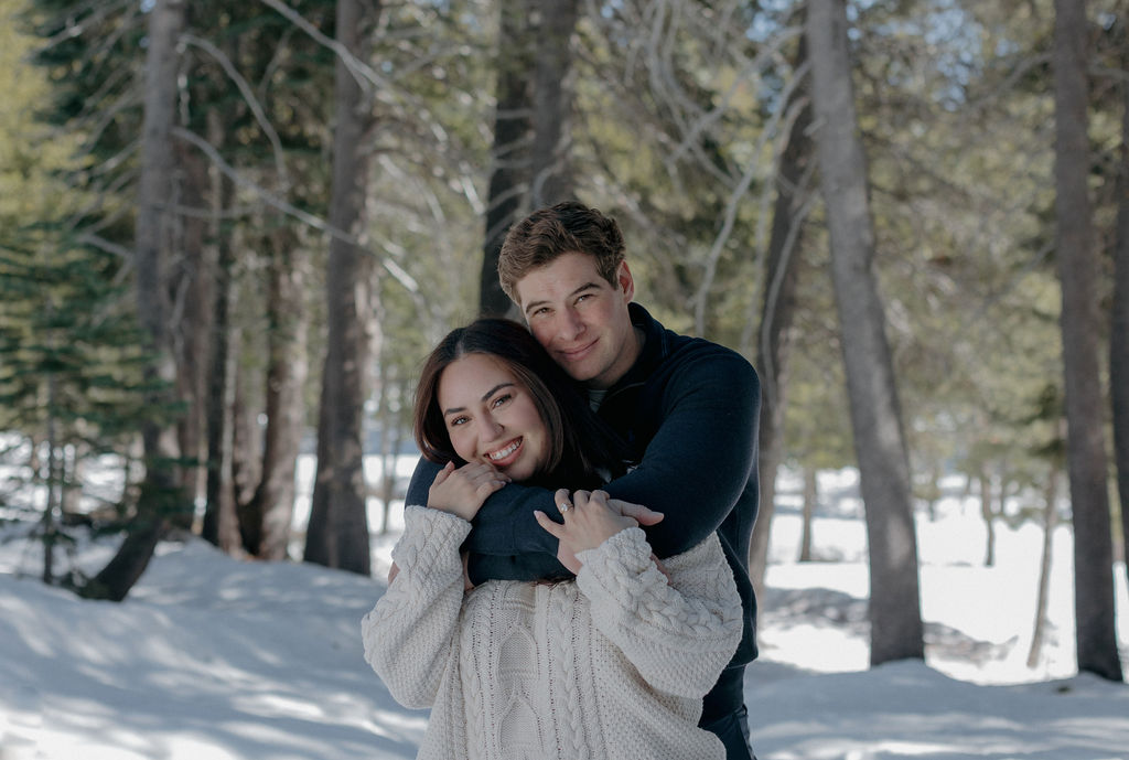 A couple taking winter engagement photos in the snow