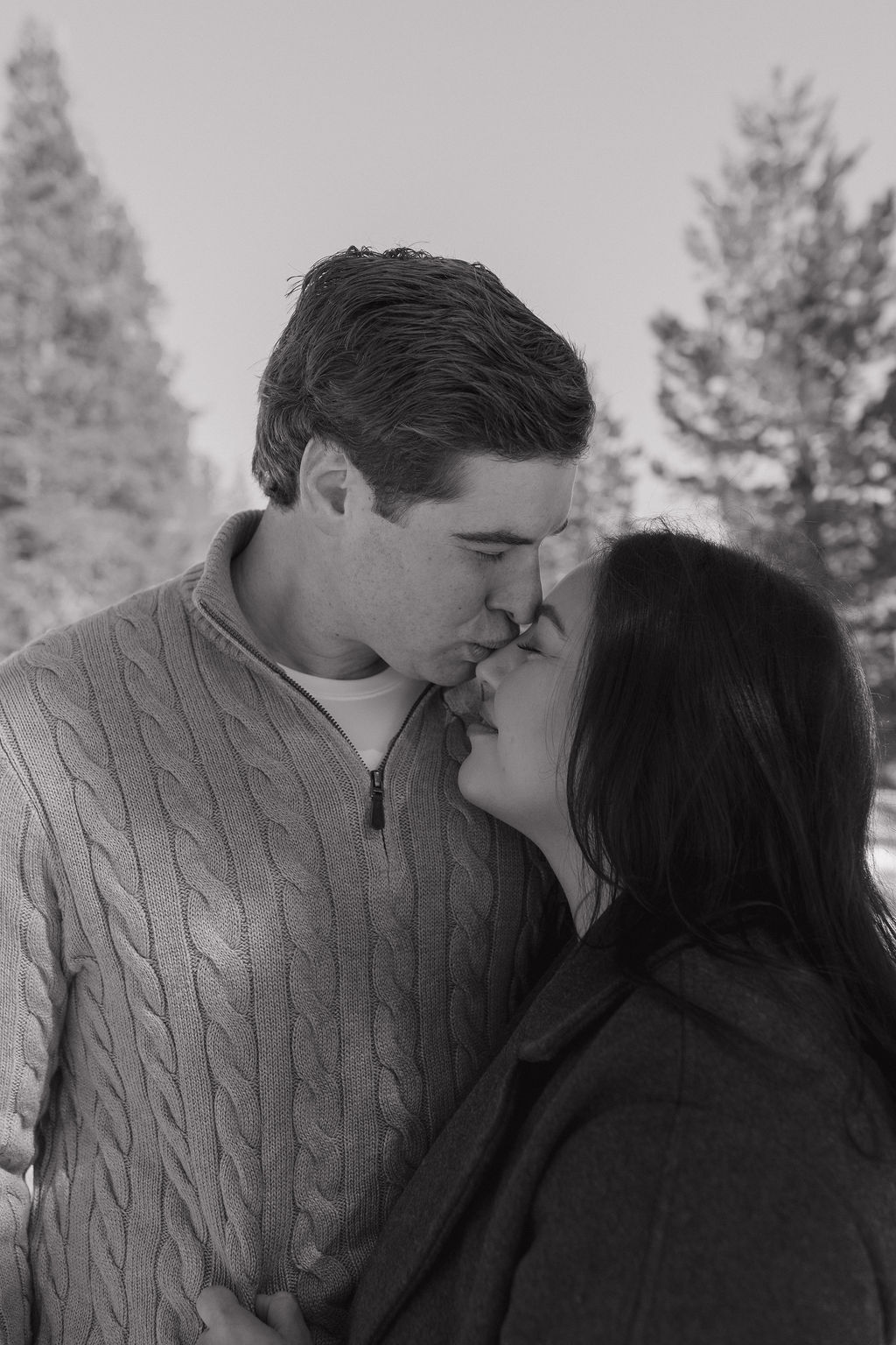 A couple posing for engagement photos in the snow