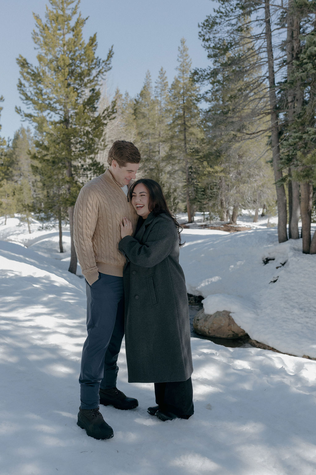 A couple posing for winter engagement photos in the snow