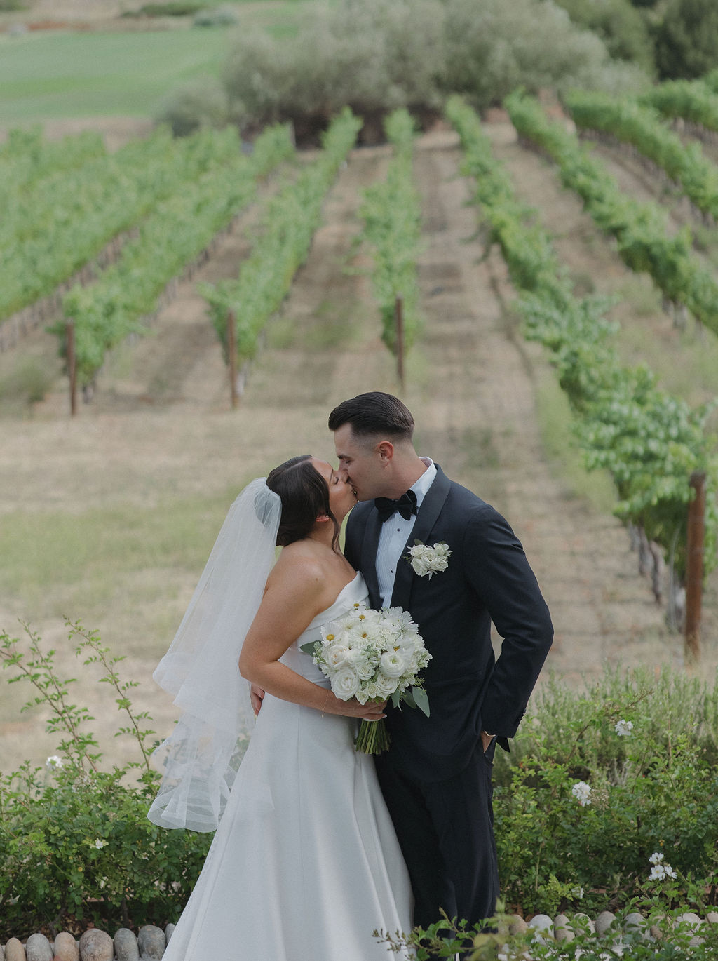 A bride and groom taking photos in the vineyards