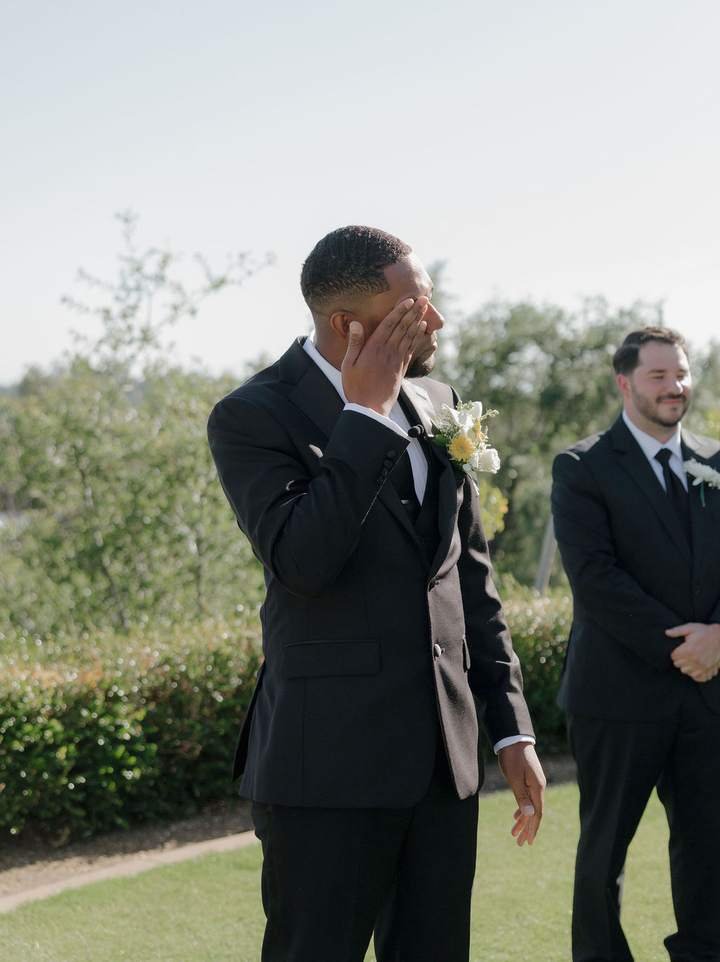 A groom crying watching a bride walk down the aisle