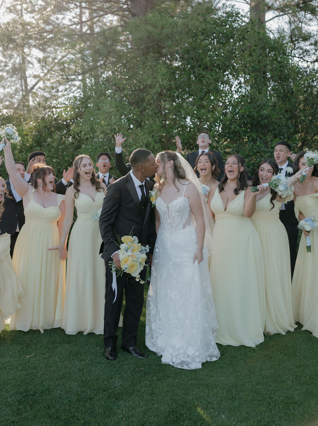 A wedding party posing for photos in butter yellow bridesmaid dresses