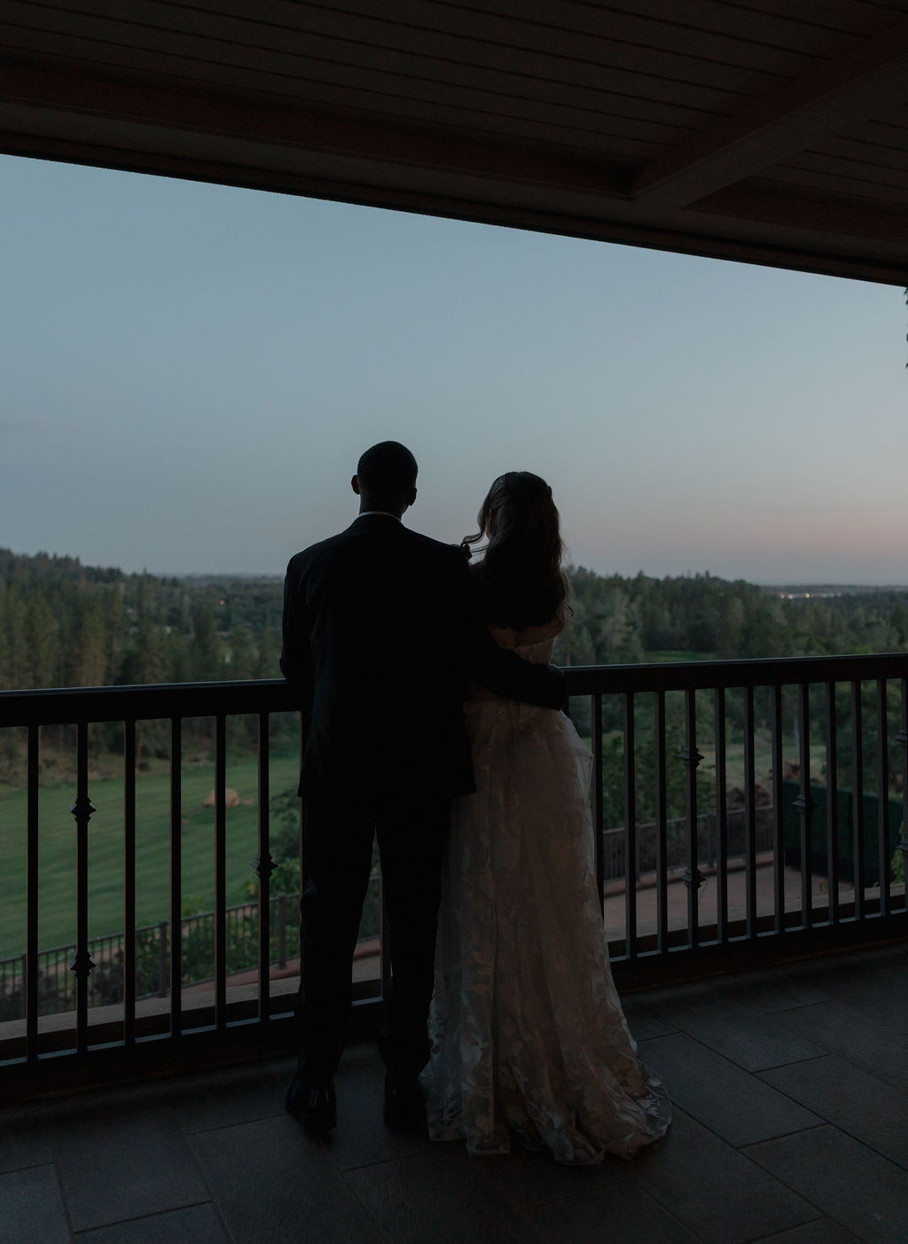 A bride and groom looking out at the views from their wedding venue